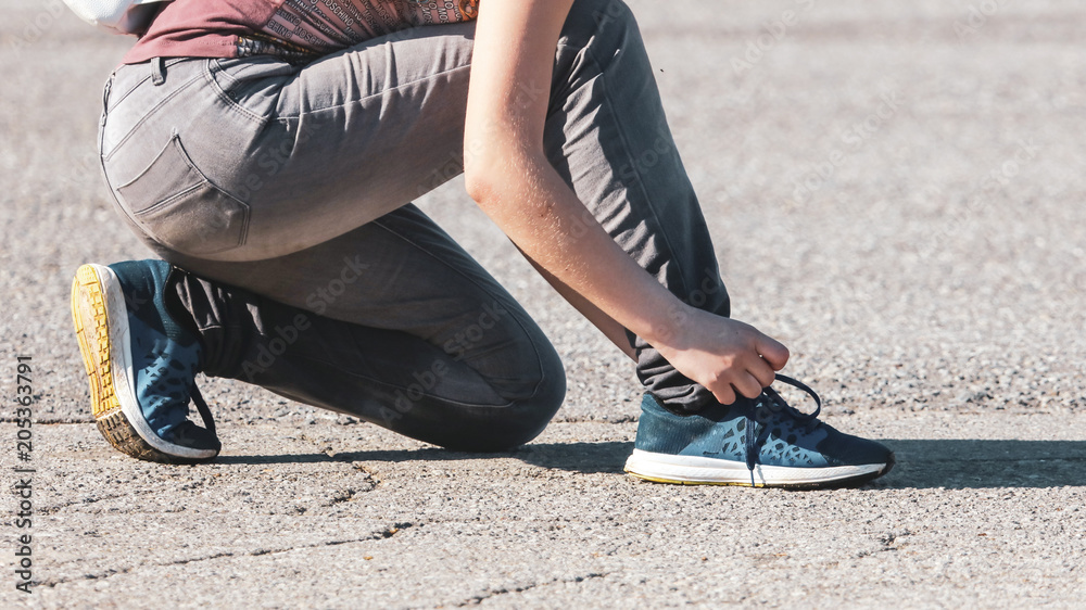 The girl ties up her shoelaces on sneakers The girl ties up her shoelaces on sneakers