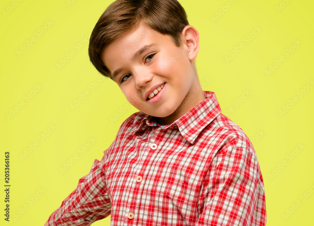 Handsome toddler child with green eyes confident and happy with a big natural smile inviting to enter over yellow background Handsome toddler child with green eyes confident and happy with a big natural smile inviting to enter over yellow background