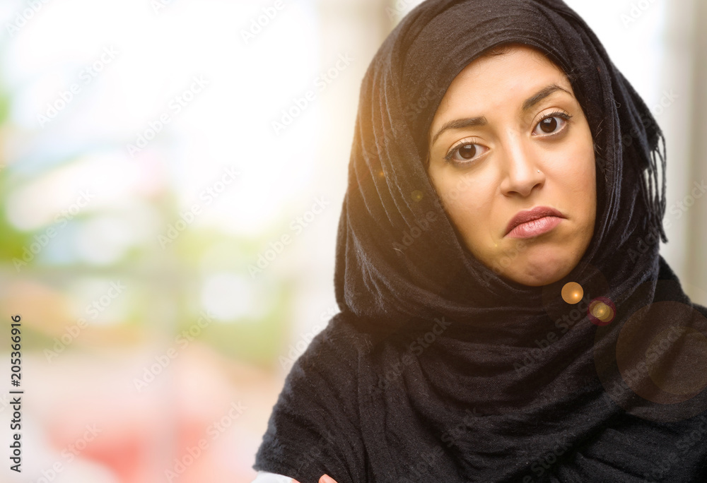 Young arab woman wearing hijab with crossed arms confident and happy with a big natural smile laughing Young arab woman wearing hijab with crossed arms confident and happy with a big natural smile laughing