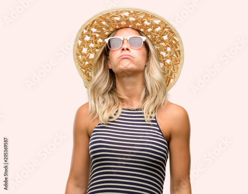 Young woman using sunglasses wearing summer hat with sleepy expression, being overworked and tired photo