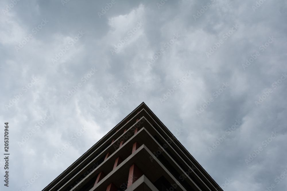 Bottom view of modern building in business district against overcast sky Bottom view of modern building in business district against overcast sky