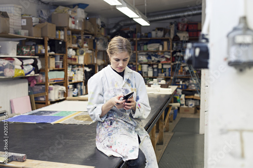 Textile designers checking her phone in workshop