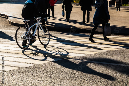 Shadows and silhouettes of people crossing the city street