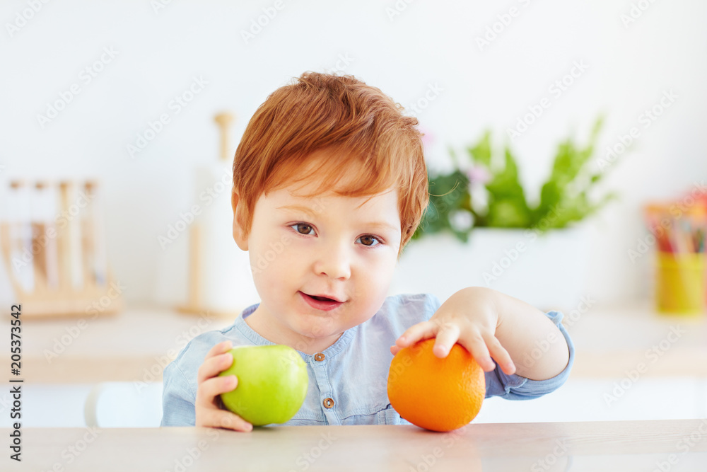 cute redhead toddler baby holding fresh apple and orange fruits cute redhead toddler baby holding fresh apple and orange fruits