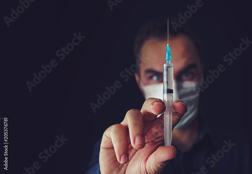 Fotografie Angry doctor woman in a medical mask holds a syringe