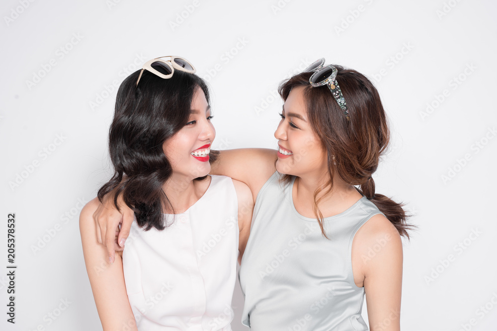 Two fashionable women in nice dresses standing together and having fun Two fashionable women in nice dresses standing together and having fun