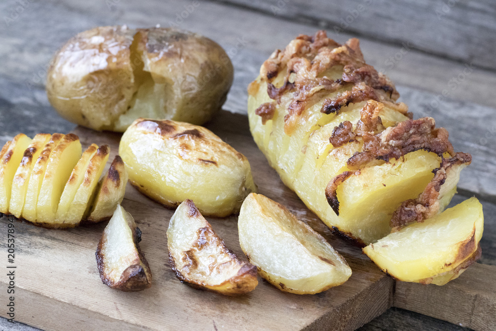 Baked potatoes of different kinds located on a wooden background in rustic style close-up Baked potatoes of different kinds located on a wooden background in rustic style close-up