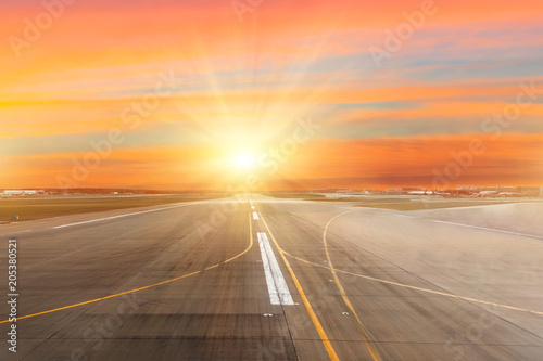 Runway at the airport the horizon at sunset in the center of the sun light rays. © aapsky