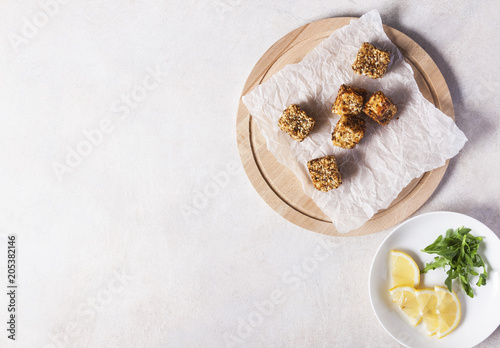 Cheese, diced and fried in batter and sesame on a wooden Board. White background. Top view.