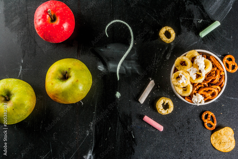 Healthy and unhealthy snack concept with crackers, chips and apples on black chalkboard Healthy and unhealthy snack concept with crackers, chips and apples on black chalkboard