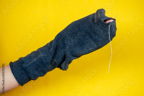old smelly, leaky sock and needle and thread on a yellow background