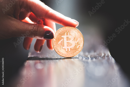 Female hand holding golden bitcoin coin, symbol of crypto currency