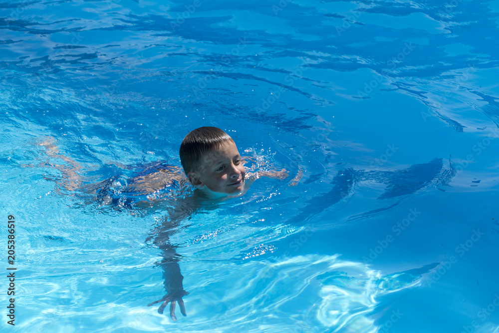 Young boy swimmimng in the pool for first time