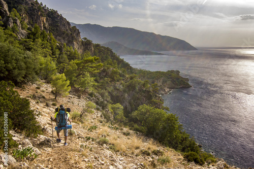 tourist with backpack standing on a cliff in mountains near mediterranean sea © sergeyonas