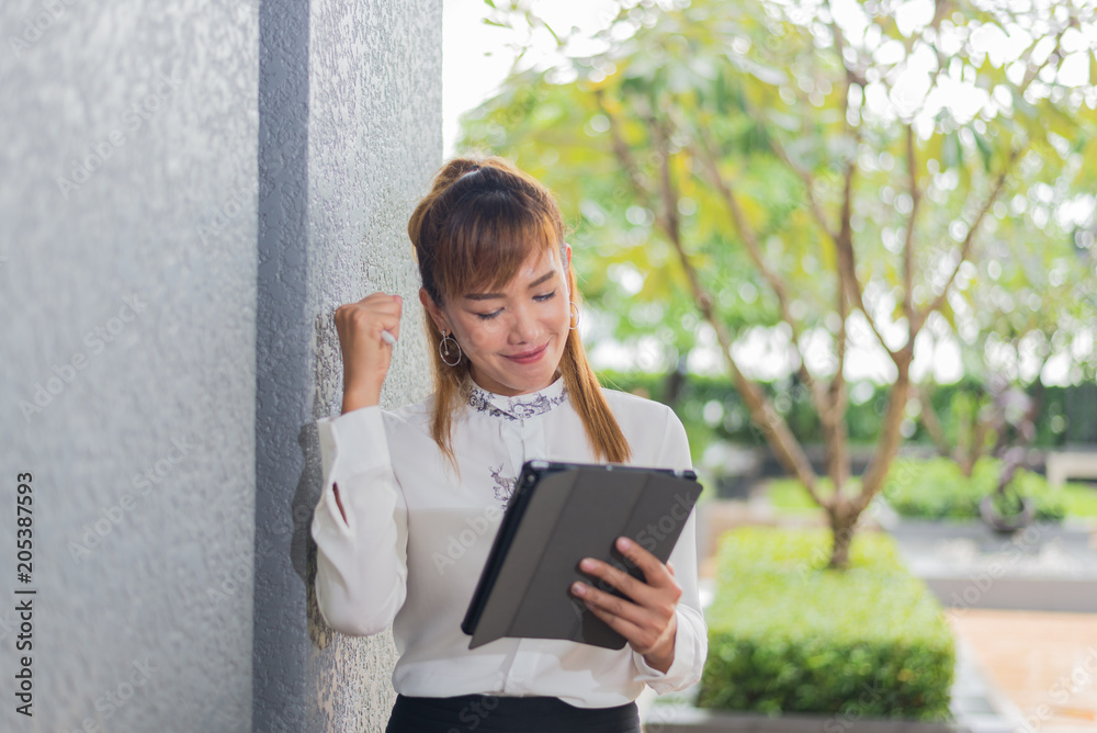 Fototapeta premium Elegant modern business woman working on tablet screen in an urban environment