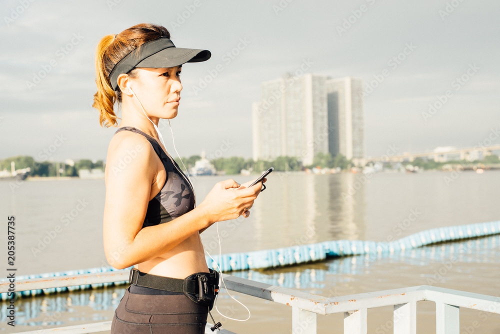 Sporty Woman listening to music with earphones in city
