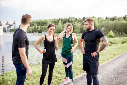 Fototapeta Naklejka Na Ścianę i Meble -  Sports team having fun standing together after the training outdors in the park near the lake