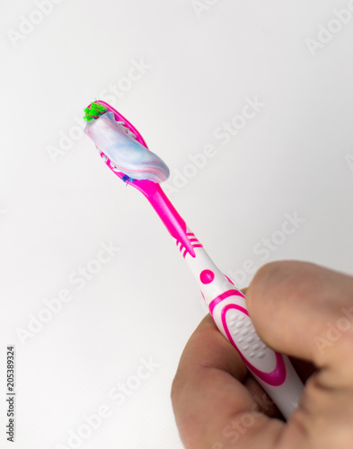 Toothbrush with squeezed toothpaste in her hand on a white background.