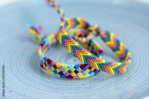 Two handmade homemade colorful natural woven bracelets of friendship isolated on light blue background