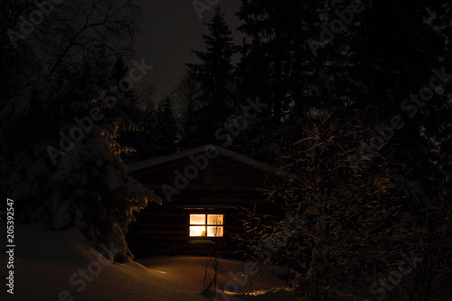 Snowy night with a Christmas candle in a hermit hut