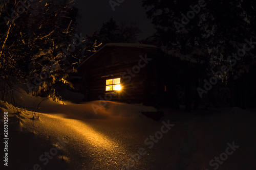 Snowy night with a Christmas candle in a hermit hut