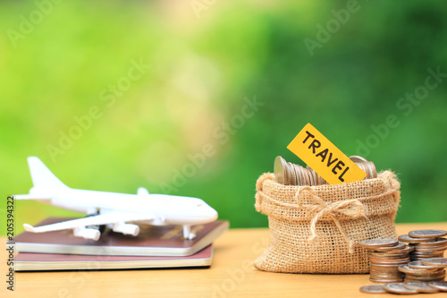 Saving planning for Travel budget of holiday concept, Stack of coins money in the bag and airplane on passport with natural green background photo
