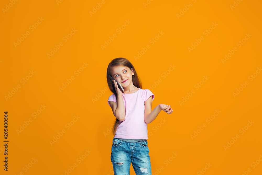 The happy teen girl standing and smiling with phone The happy teen girl standing and smiling with phone