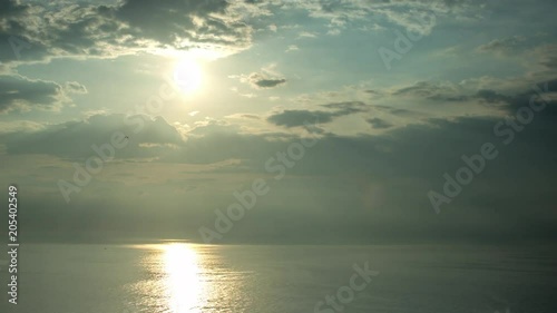 timelapse shot of beautiful moody storym sky withclouds hiding the sun and reflection in the sea below photo