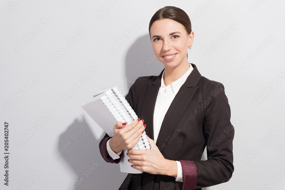 Young smiling businesswoman holding books in her hands. Fashion style photoshoot with har light source Young smiling businesswoman holding books in her hands. Fashion style photoshoot with har light source