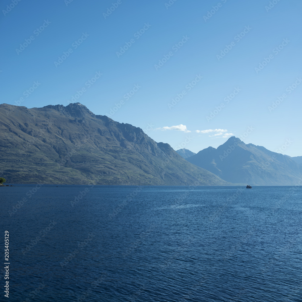 Landscape of mountains in front of a lake. Daytime scene, blue and clear sky. New Zealand.