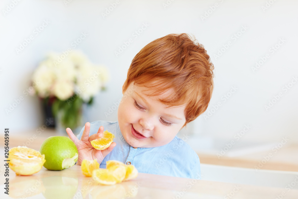 cute redhead toddler baby tasting orange slices and apples at the kitchen cute redhead toddler baby tasting orange slices and apples at the kitchen