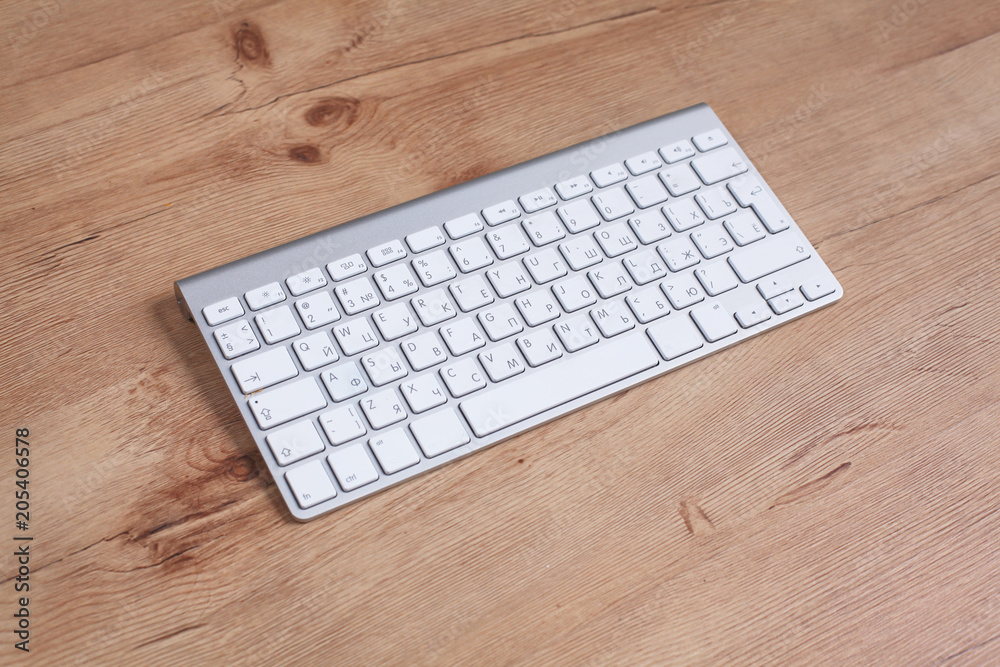 Modern aluminum keyboard on the wooden table in the office Modern aluminum keyboard on the wooden table in the office