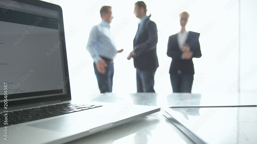 Focus on laptop on the table. Blurred people on background Focus on laptop on the table. Blurred people on background