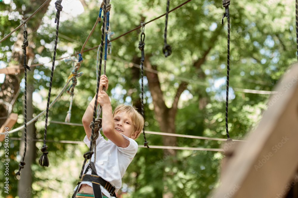 Portrait of happy little boy having fun in extreme rope park