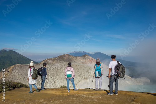 Group of tourists who are standing views on crater Kawah Ijen, Indonesia.