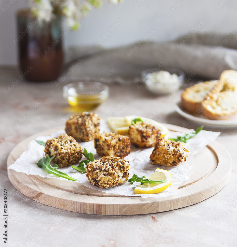 Cheese, diced and fried in batter and sesame on a wooden Board. White background. Cheese, diced and fried in batter and sesame on a wooden Board. White background.