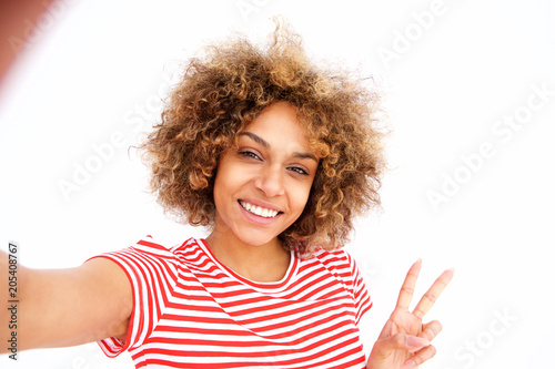 Portrait of beautiful young african american woman taking selfie against white wall