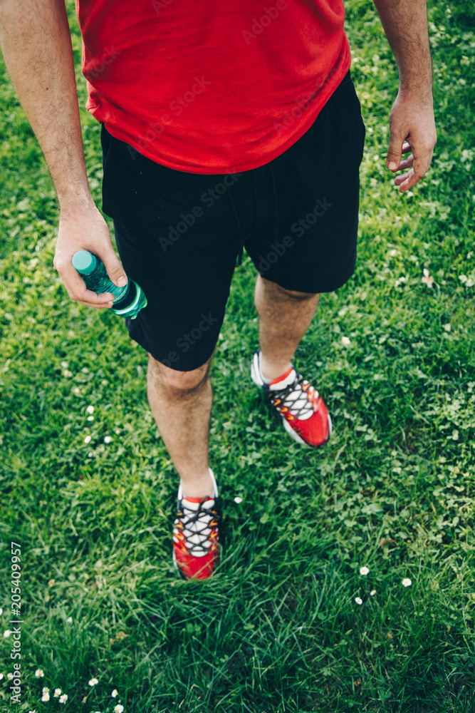 Close-up of man wearing running shoes and holding a water bottle Close-up of man wearing running shoes and holding a water bottle