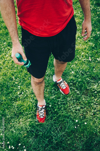 Close-up of man wearing running shoes and holding a water bottle
