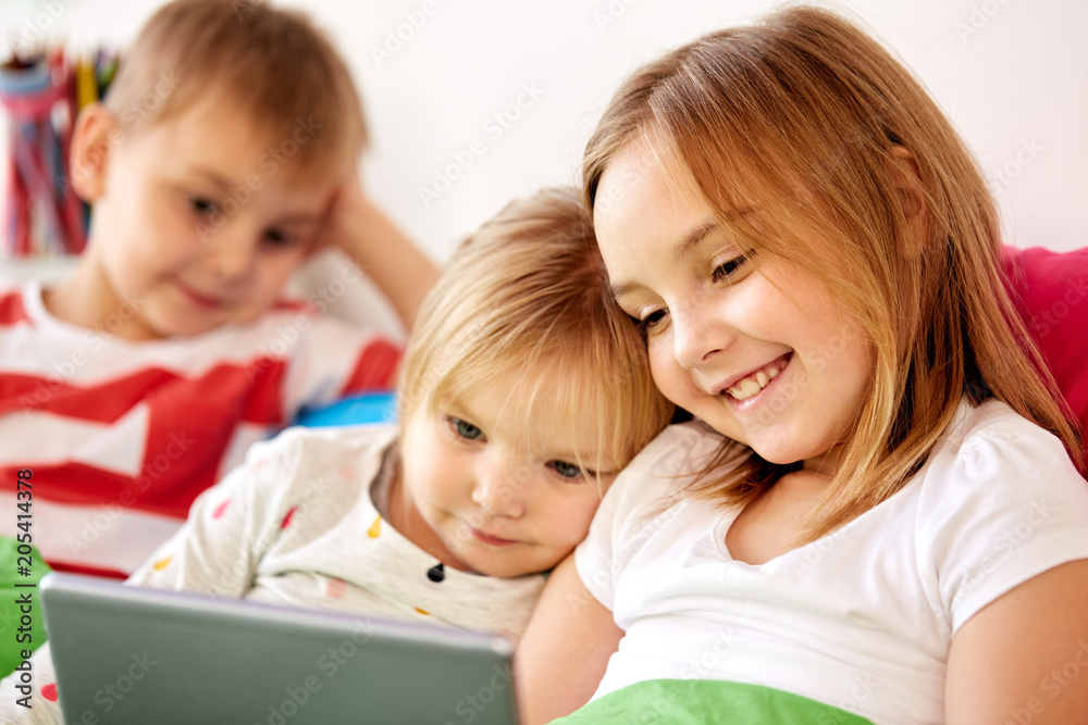 childhood, technology and family concept - happy little kids with tablet pc computer in bed at home childhood, technology and family concept - happy little kids with tablet pc computer in bed at home