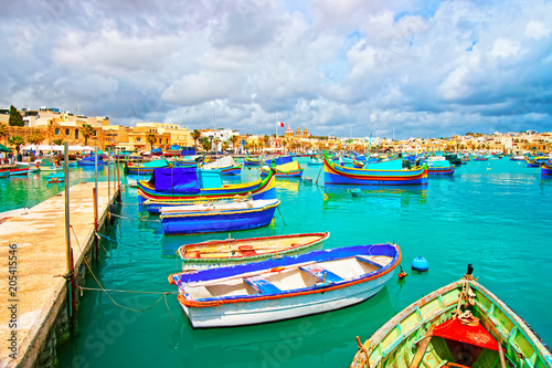 Luzzu boats in Marsaxlokk Port embankment of bay Mediterranean sea photo