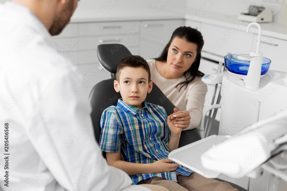 medicine, dentistry and healthcare concept - mother and son visiting dentist at dental clinic medicine, dentistry and healthcare concept - mother and son visiting dentist at dental clinic