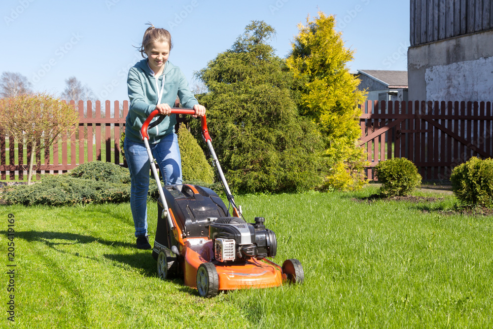 teenage girl working in garden, mowing grass with lawn-mower teenage girl working in garden, mowing grass with lawn-mower
