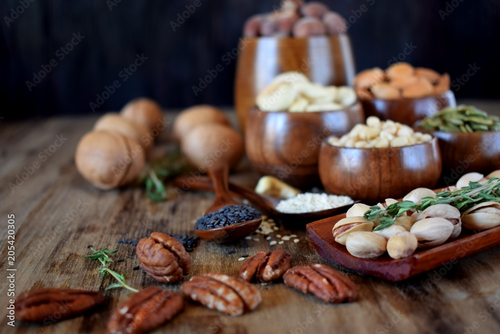 Different nuts and seeds in wooden spoons and bowls