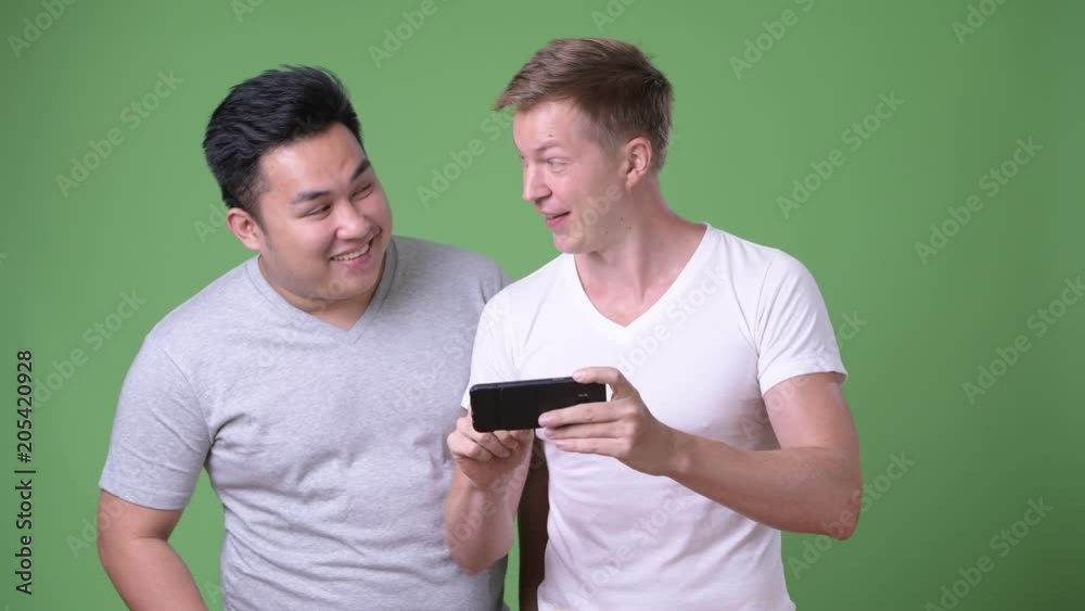 Two young multi-ethnic handsome men together against green background Two young multi-ethnic handsome men together against green background