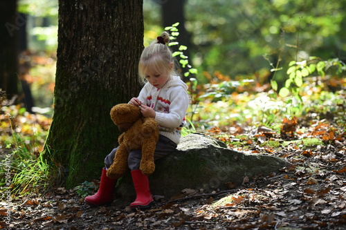 Childhood, game, fun, active rest and activity. Little girl in autumn forest. Child with teddy bear in fairy tale woods. Kid with toy enjoy fresh air outdoor