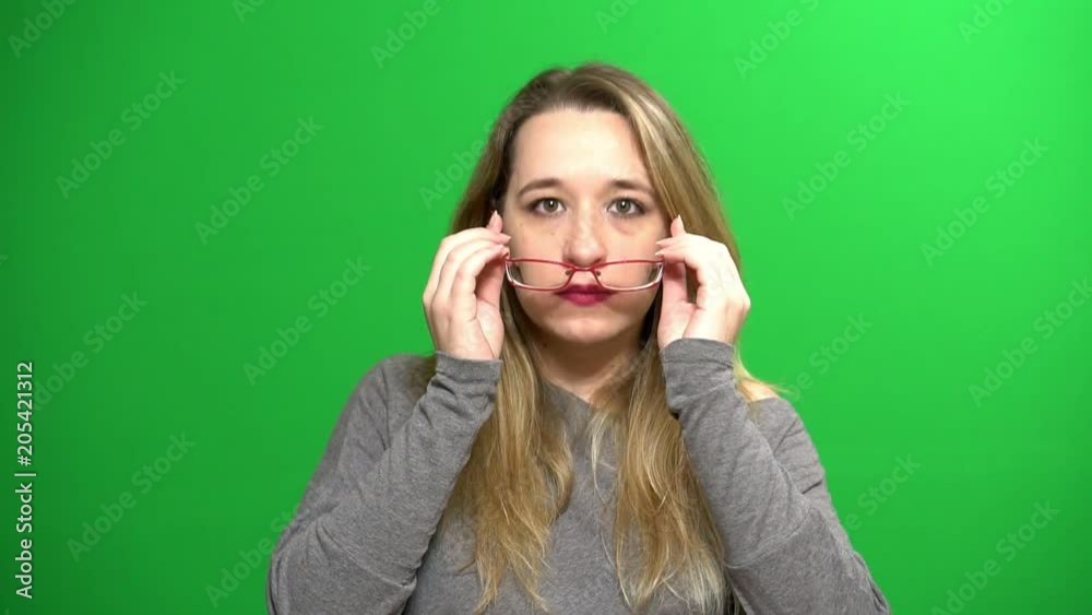 Young girl posing. She examines the glasses and puts on. Background - green screen. Young girl posing. She examines the glasses and puts on. Background - green screen.