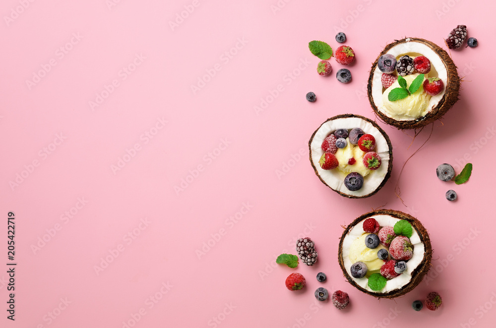 Coconut ice cream with fresh berries in coconuts halves on pink background with copy space. Top View. Pop art design, creative summer concept. Food in minimal flat lay style. Coconut ice cream with fresh berries in coconuts halves on pink background with copy space. Top View. Pop art design, creative summer concept. Food in minimal flat lay style.