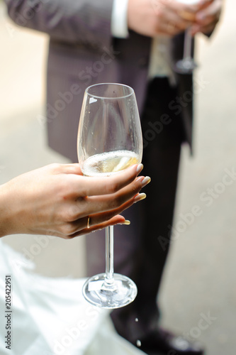 A female hand holds a glass of champagne. Drops of champagne on the hand.