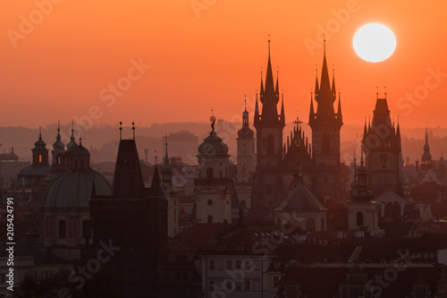 Twilight in historical city. Magical picture of tower with orange sun in Prague,